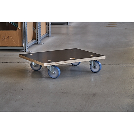 Plate with wheels on concrete floor. In a warehouse. Wooden plate with boreholes on four wheels.
