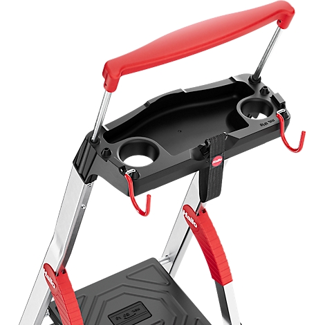 Detailopname van een zwart schap voor een ladder met rode haken en handvat. De ladder is gedeeltelijk van metaal.