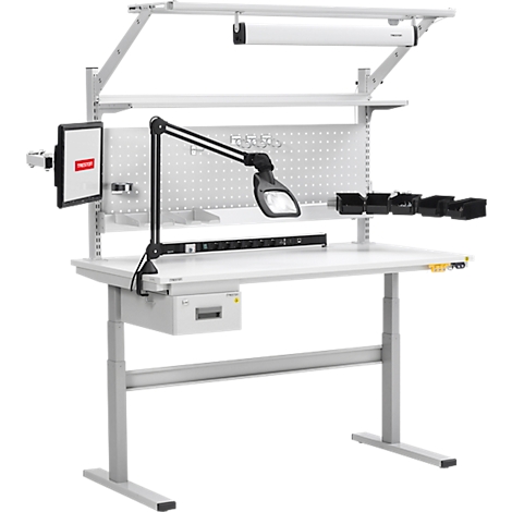 Un établi blanc réglable en hauteur avec panneau perforé, lampe, moniteur et étagères pour appareils électroniques.