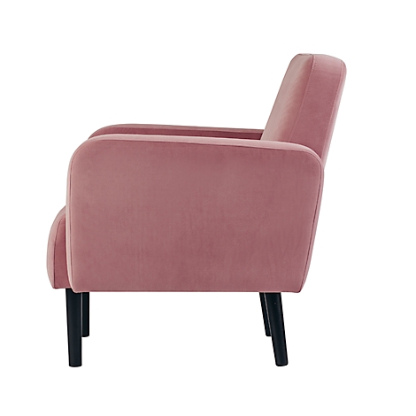 Roze fluwelen fauteuil in profiel met zwarte poten. Zachte vorm, elegante uitstraling.