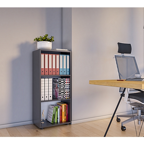 Gray bookshelf with files and books, next to a desk with an office chair. A plant stands on top of the shelf.