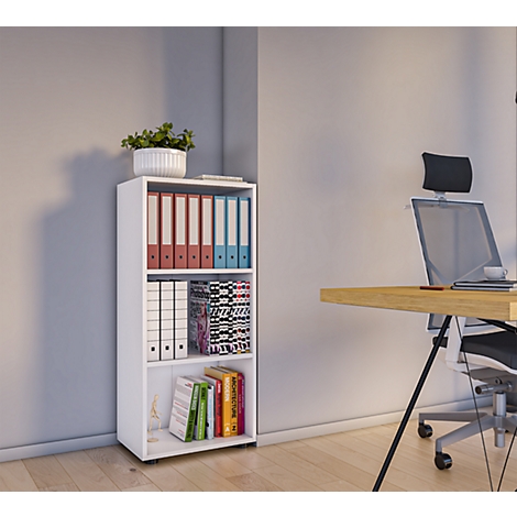 White bookcase with binders, books, and a potted plant. A desk with chair in the background.
