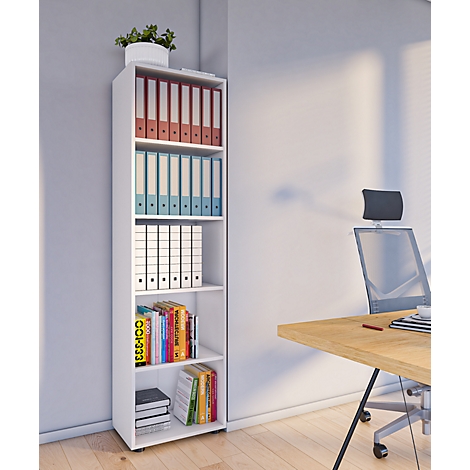 White bookshelf with binders, books and plant in the corner. Behind it a desk and office chair.