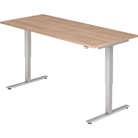 A height-adjustable desk with a light brown table top and silver legs.