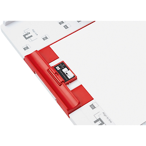 Close-up of a white, red, and black paper alignment tool. A sheet of paper is fixed inside.