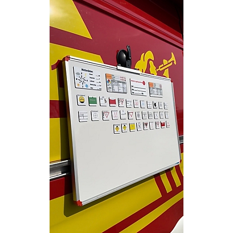 Magnetisches Whiteboard an einer roten und gelben Fahrzeugwand mit diversen Symbolen für Feuerwehreinsätze.