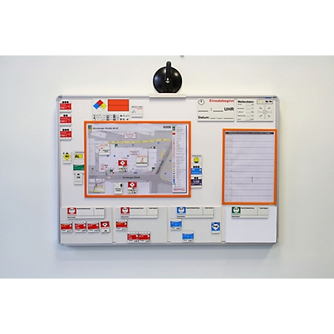 Ein Whiteboard an einer weißen Wand mit einem Gebäudeplan, Infofeldern und beschrifteten Magnetschildern für den Notfall.