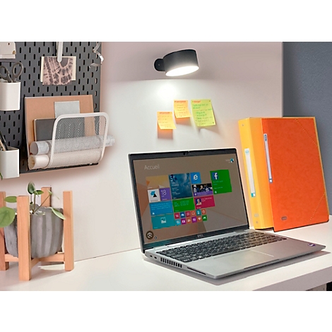 Ordinateur portable sur un bureau blanc, éclairé par une lampe noire. Dossiers orange et post-it à côté.