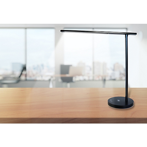 Schlanke, schwarze LED-Schreibtischlampe auf einer hellen Holzoberfläche vor unscharfem Büro-Hintergrund.