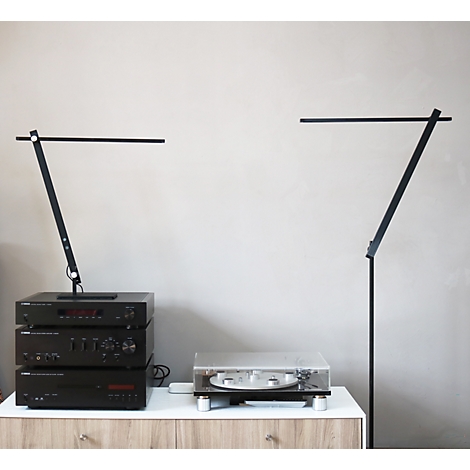 Zwei minimalistische, schwarze LED-Lampen stehen auf einem Sideboard neben einer Stereoanlage und einem Plattenspieler.