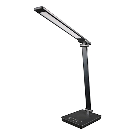Dunkle Schreibtischlampe mit rechteckigem Leuchtkopf. Sie steht auf einem quadratischen Fuß. Der Leuchtkopf ist ausgerichtete.