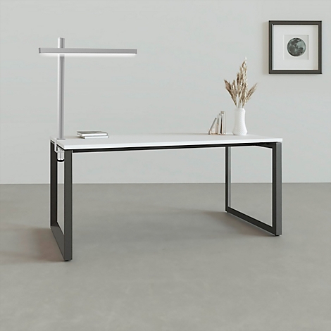 Schreibtisch mit weisser Oberfläche, schwarzem Gestell, Lampe und Deko-Elementen.