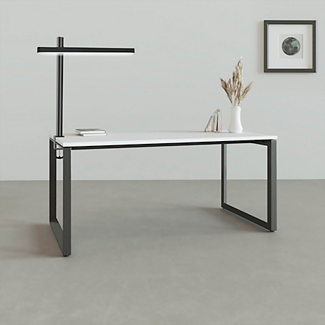 Schreibtisch mit schwarzem Gestell und weisser Platte. Darüber eine schwarze Lampe. Auf dem Tisch: Buch, Vase mit Getreide. Bild mit Mond. 