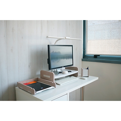 Werkplek met monitor, toetsenbord, bak, bureaulamp en raam met jaloezieën.