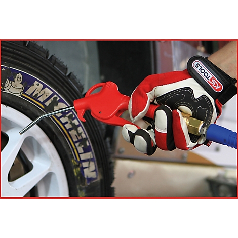 Person mit Handschuh hält rote Luftpistole an Reifen. Der Reifen ist mit Michelin beschriftet.
