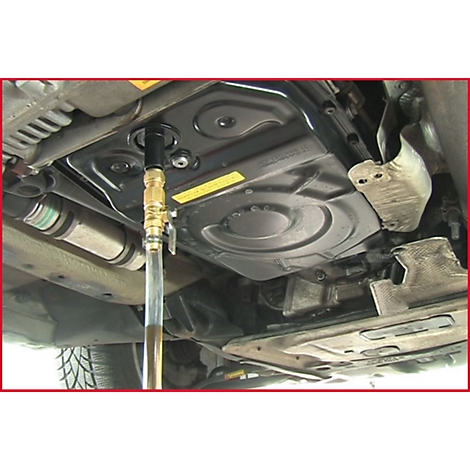 Nahaufnahme eines Autos von unten. Ein Schlauch wird in die Getriebeölwanne eingeführt.