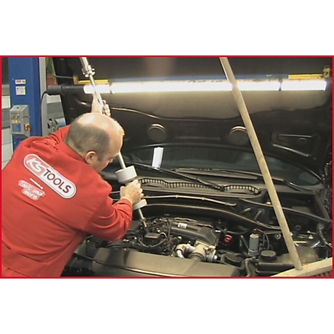 Mechaniker in rotem Overall von KS TOOLS arbeitet an einem Motorraum. Werkzeug im Einsatz.