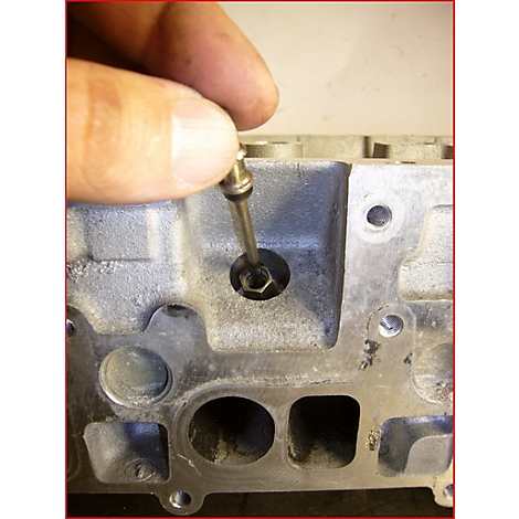 Hand hält Werkzeug in Zylinderkopf. Detailaufnahme zur Reparatur oder Wartung.