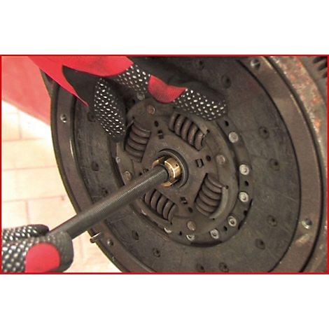 Nahaufnahme einer Kupplung, die von einem Mechaniker mit Werkzeug bearbeitet wird. Handschuhe schützen Hände.