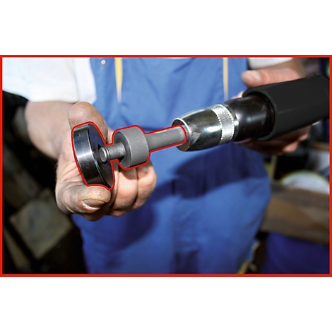 Nahaufnahme einer Hand, die ein Werkzeug hält. Der Fokus liegt auf dem Aufsatz und der Spitze eines schwarzen Druckluftschraubers.