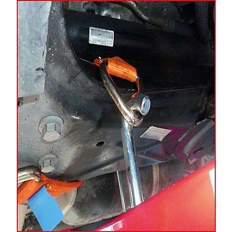 Nahaufnahme von Werkzeug unter einem Auto. Ein Hebezeug mit orangefarbenen Gurten ist befestigt, daneben ein Schraubenschlüssel.