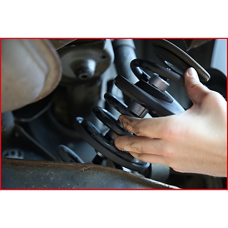 Hand hält einen Stoßdämpfer in einem Auto.