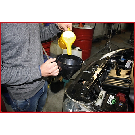 Eine Person gießt Öl mit einem gelben Trichter in einen Motor.