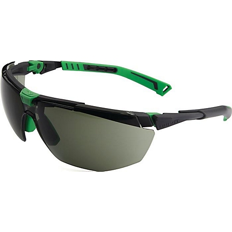Lunettes de protection avec monture noire et accents verts. Les verres sont teintés en gris. Les lunettes sont en diagonale dans l'image.