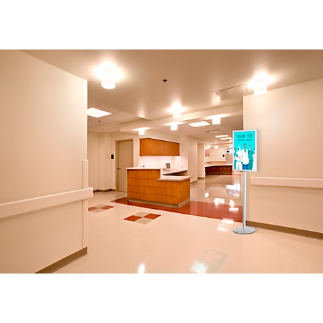 Krankenhausflur mit Rezeption, Schildern und hellem Licht.