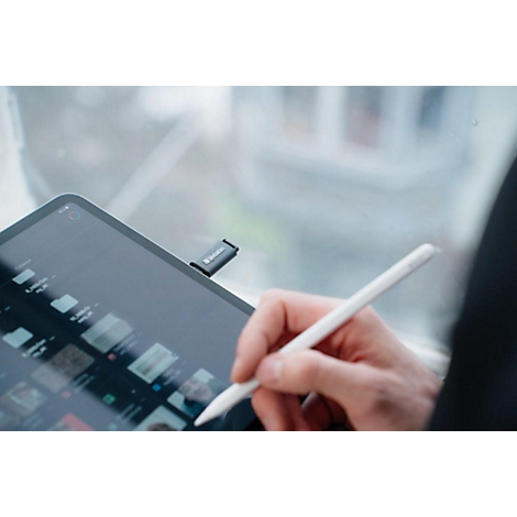 Persoon gebruikt tablet met pen. Rechts, arm en pen; links, tablet met USB-stick.