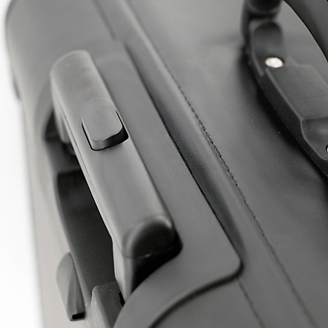Gros plan sur une valise noire. Poignées en plastique, surface semblable au cuir. La couture est visible.
