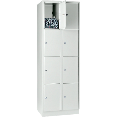 White locker with open door, a bag lies inside. Besides the open compartment, other compartments are closed.