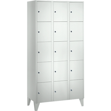 White cabinet with 15 doors, on legs. Each door has a small knob.