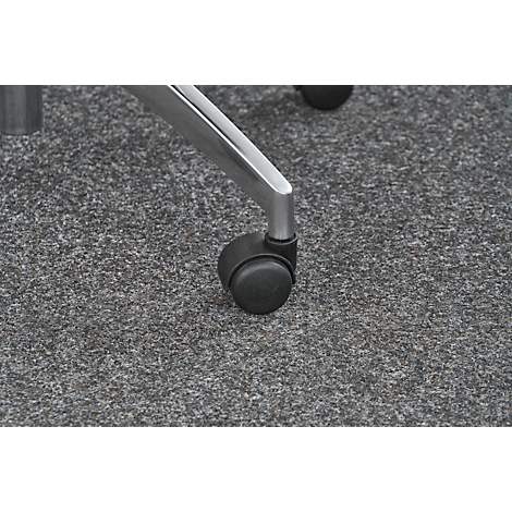 Close-up of a chair wheel and leg. The wheel is black, the leg silver. The floor is gray mottled.