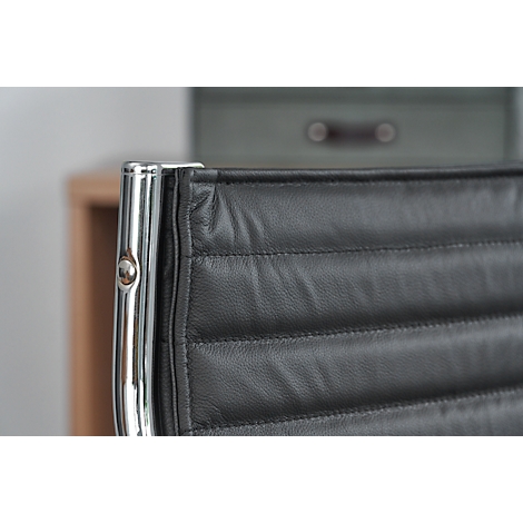 Close-up of a black leather chair. The seams and frame are clearly visible.