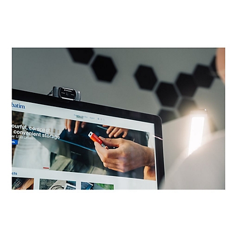 Ein Laptop mit einer Webcam, auf dem ein Mann einen roten USB-Stick auf einer Website betrachtet.