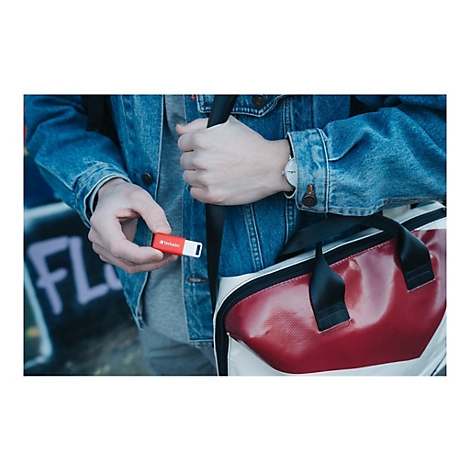 Person hÃ¤lt roten USB-Stick. In der anderen Hand eine Tasche. Denim-Jacke und Uhr.