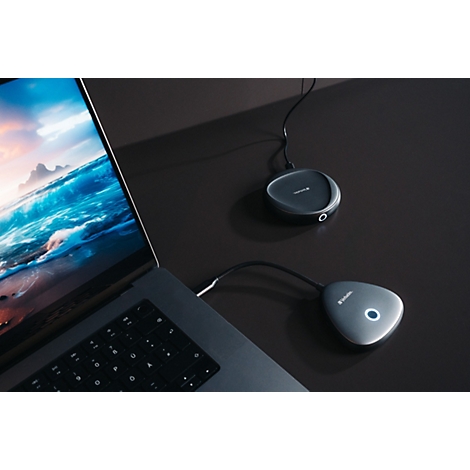 Laptop auf dunklem Schreibtisch mit zwei verbundenen, dreieckigen Konferenz-Hubs, einer leuchtet blau.