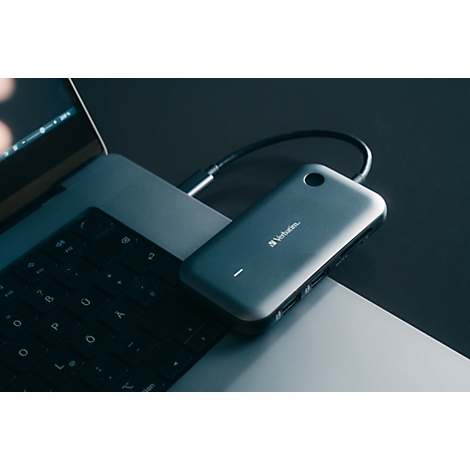 Ein grauer Verbatim USB-C-Hub liegt auf einem Laptop und ist per Kabel angeschlossen.
