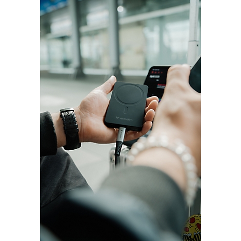 Person hält eine schwarze Powerbank mit einem angeschlossenen Ladekabel in der Hand.