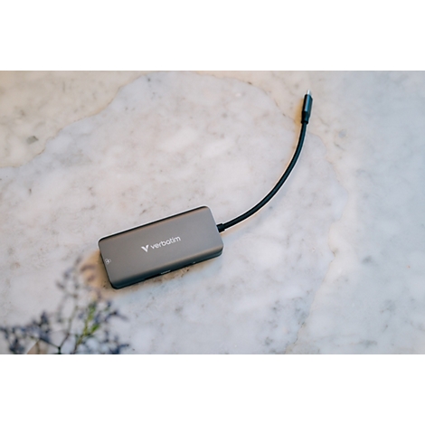 Grauer USB-C-Multiport-Hub der Marke Verbatim auf einem hellen Marmoruntergrund.