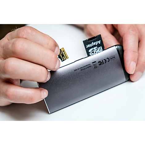 Handen die een zilveren kaartlezer, een SD-kaart en een micro SD-adapter vasthouden.