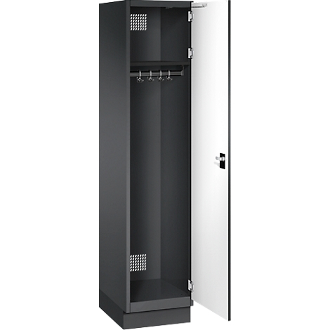 Une armoire sombre avec une porte blanche ouverte. À l'intérieur: tringle à vêtements, crochets, grille d'aération. L'armoire repose sur un socle.