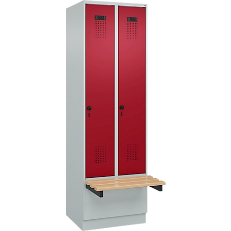 Un casier avec deux portes rouges et un banc en bois. Les portes ont des fentes de ventilation et des trous de serrure.