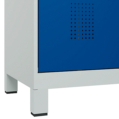 Gros plan d'une armoire bleue avec cadre et pieds blancs. L'élément bleu présente un motif de trous.