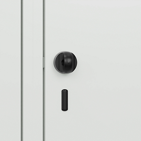 Gros plan d'un vantail de porte blanc avec une poignée de porte et une clé noires. La poignée de porte est ronde, en dessous se trouve la clé.