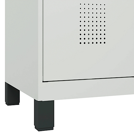 Détail d'une armoire blanche avec une base noire. Une série de trous de ventilation est visible en haut à droite.