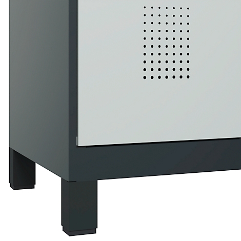 Gros plan d'une armoire grise, dont la porte est perforée de petits trous. L'armoire repose sur des pieds rectangulaires.