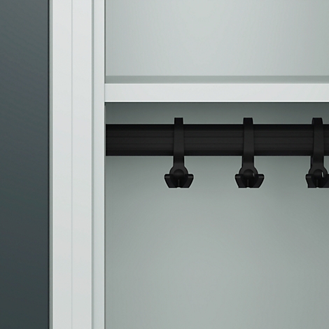 Gros plan détaillé d'un cintre noir à l'intérieur d'une armoire. Paroi d'armoire claire avec un fond sombre.