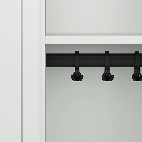 Gros plan d'une tringle à vêtements noire avec des crochets à l'intérieur d'une armoire blanche.